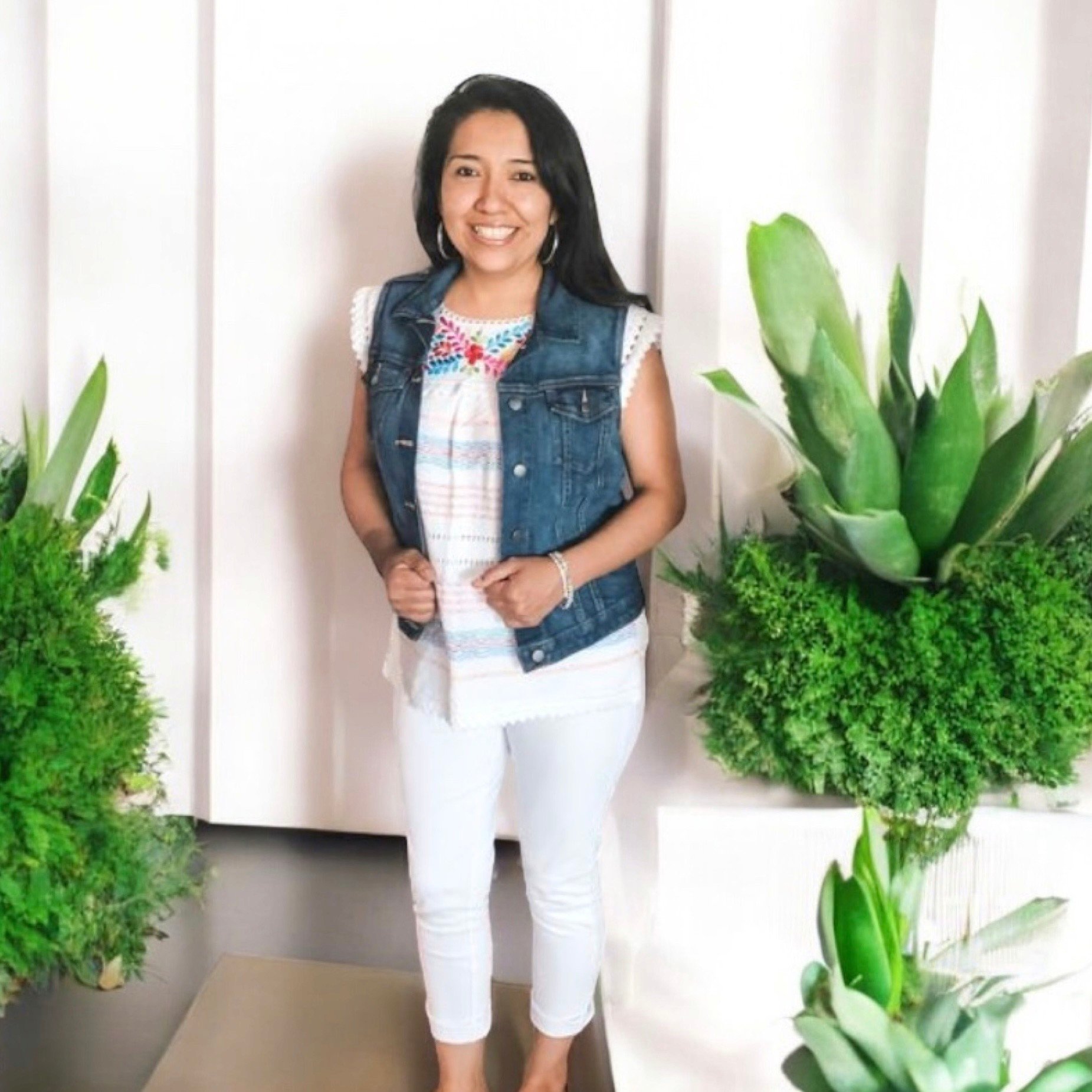 Bia, the owner of Susa's Sweets and Balloons, standing beside decorative plants in Lincoln, Nebraska