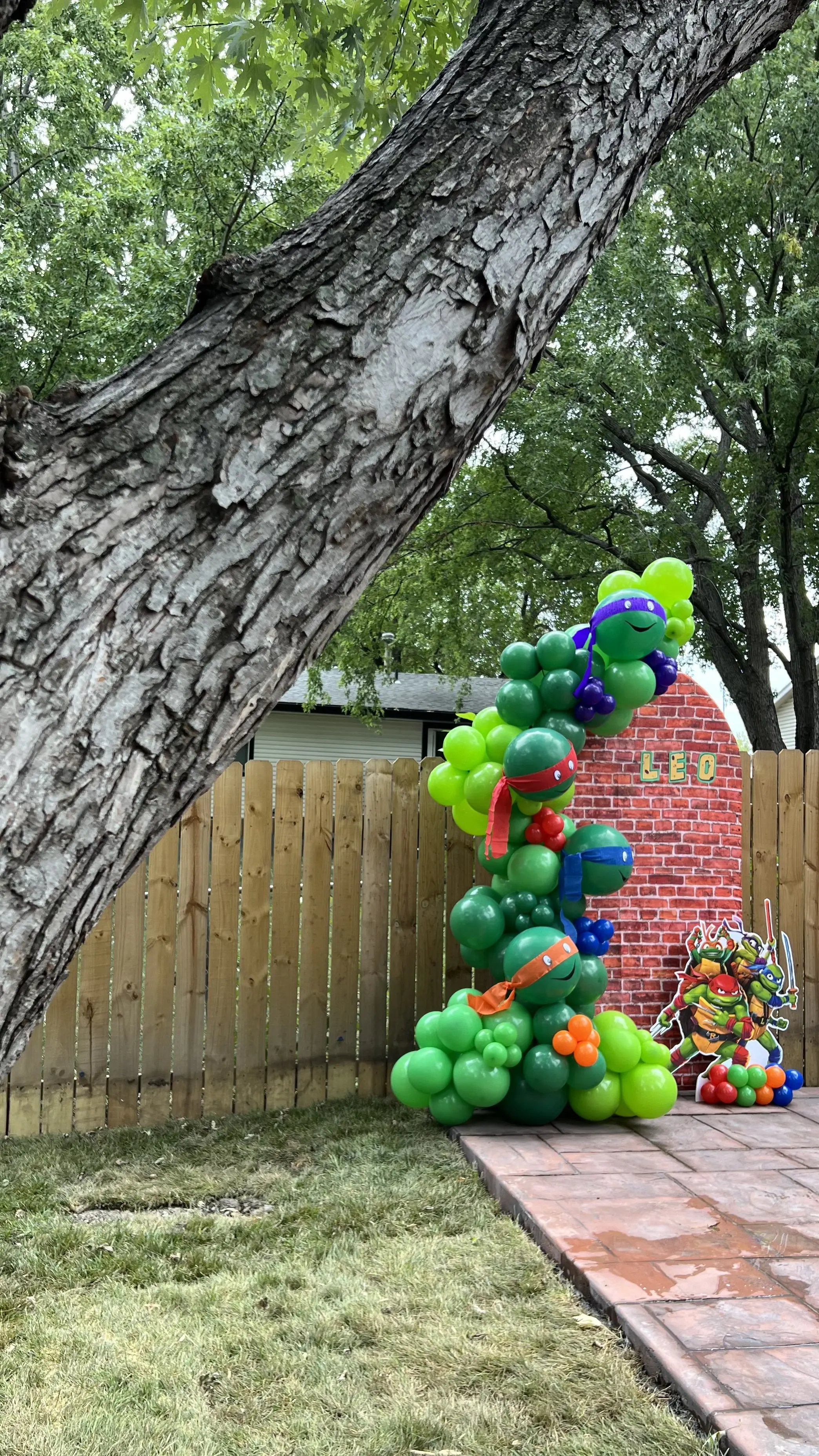 Green dinosaur balloon column built for an outdoor birthday in Lincoln